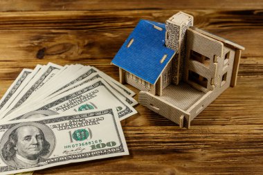 Ev modeli ve ahşap arka planda 100 dolarlık banknotlar. Emlak yatırımı, ev kredisi, ev kredisi, emlak konsepti