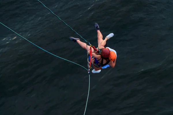 Couple rope jumping from high altitude of bridge. Couple bungee jumping from pedestrian bridge over a river