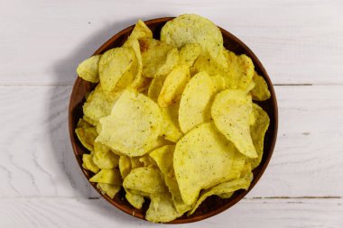 Beyaz ahşap masada patates cipsi tabağı. Üst görünüm