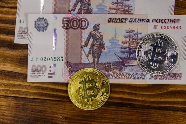 Ahşap arka planda altın ve gümüş Bitcoins ve 500 Rus ruble faturaları