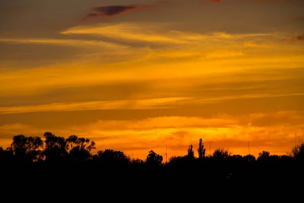 村や木々のシルエットにオレンジの夕日 — ストック写真