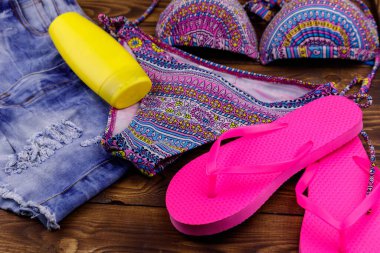 Ahşap arka plan üzerinde beachwear kümesi. Güneş kremi, Mayo, şort ve parmak arası terlik. Yaz tatil kavramı