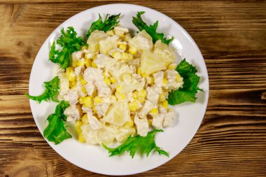 Tavuk göğsü, tatlı mısır, konserve ananas ve ahşap masada mayonez ile Şenlikli salata