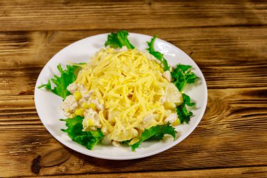 Tavuk göğsü, tatlı mısır, konserve ananas, peynir ve ahşap masada mayonez ile Şenlikli salata