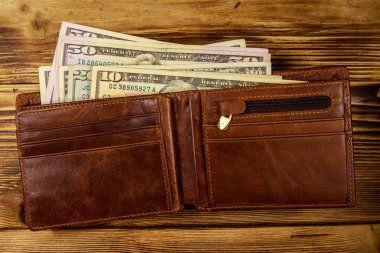 Ahşap masanın üzerinde Amerikan doları olan açık cüzdan. Üstte görüntü