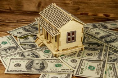 Ev modeli ve ahşap arka planda 100 dolarlık banknotlar. Emlak yatırımı, ev kredisi, ev kredisi, emlak konsepti