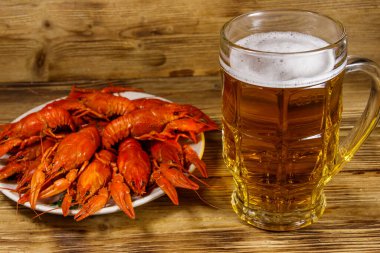 Haşlanmış kerevit ve bir kupa bira ahşap masada.
