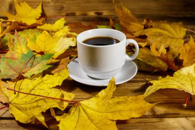 Bir fincan kahve ve sonbahar akçaağaç yaprakları ahşap masada. Sonbahar konsepti