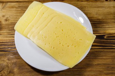 Tahta masadaki bir tabakta peynir dilimleri. Üst görünüm