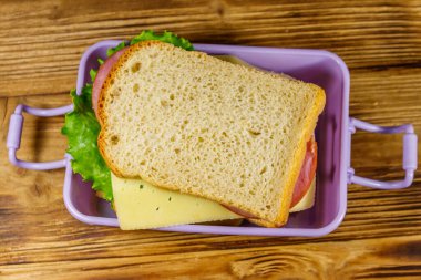 Tahta bir masanın üzerinde sandviçlerle beslenme çantası. Üst görünüm