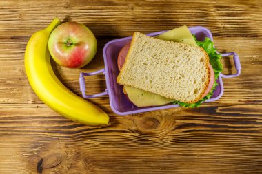 Sandviç, muz ve elmayla dolu bir beslenme çantası. Üst görünüm