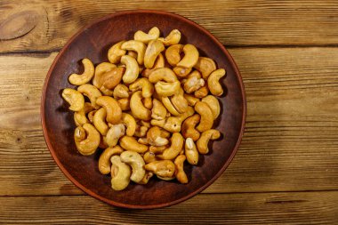 Ahşap bir masada kavrulmuş kaju fıstıklı seramik tabak. Üst görünüm