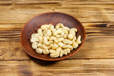 Ahşap bir masada çiğ fındıklı seramik tabak.