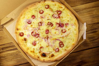 Tahta bir masanın üzerindeki karton kutuda nefis taze pizza. Üst Manzara. Yemek teslimatı, fast food, pizza teslimatı.
