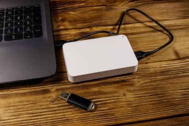 Harici HDD, tahta bir masadaki dizüstü bilgisayara ve USB flash diske bağlı. Veri depolama kavramı
