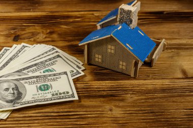 Ev modeli ve ahşap arka planda 100 dolarlık banknotlar. Emlak yatırımı, ev kredisi, ev kredisi, emlak konsepti