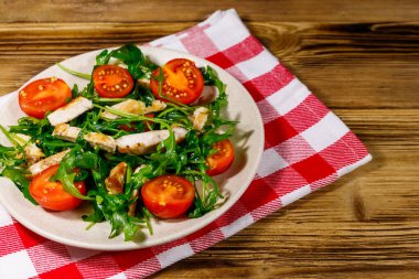 Lezzetli tavuk göğsü salatası, taze roka ve ahşap masada kiraz domatesleri.