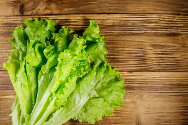 Tahta masada taze yeşil marul yaprakları. Üst görünüm