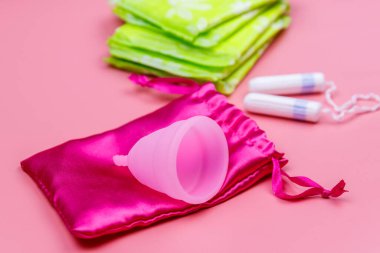 Pembe arka planda hijyenik ped, tampon ve regl kupası. Kritik günler, regl dönemi, kadın hijyeni