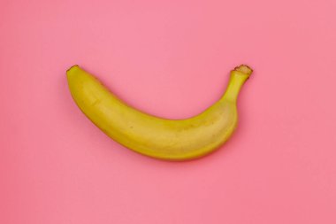 Pembe arka planda sarı muz. Üst görünüm, düz görünüm, minimal dizayn