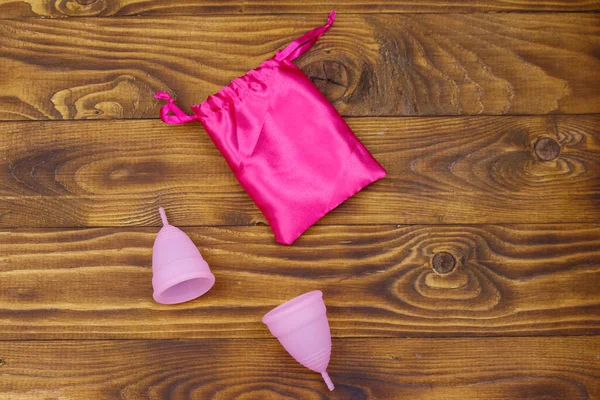 Zwei Rosa Wiederverwendbare Silikon Menstruationstassen Und Seidenbeutel Auf Holzgrund Ansicht — Stockfoto