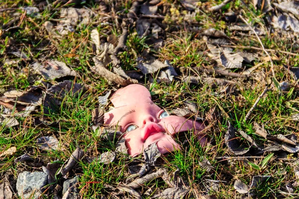 地面に葉の古い壊れた人形の顔 — ストック写真