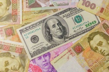 Farklı Ukrayna Hryvnia banknotlarının arka planında 100 dolarlık banknot