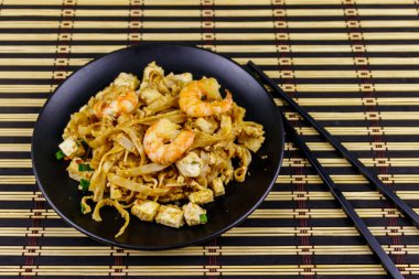 Tayland usulü kızarmış pirinç eriştesi, karides ve bambu hasırında soya peyniri. Tayland yemeği.