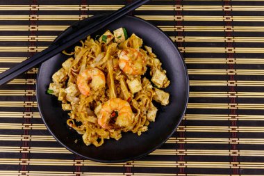 Tayland usulü kızarmış pirinç eriştesi, karides ve bambu hasırında soya peyniri. Üst Manzara. Tayland yemeği.