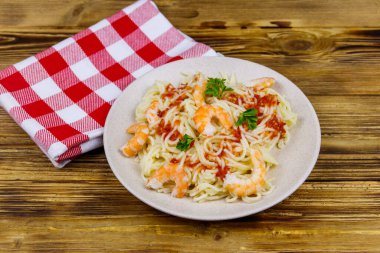 Karidesli makarna, domates sosu ve ahşap masada maydanoz.