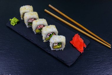 Uramaki suşisi siyah tahtada surimi ile yuvarlanır.