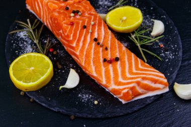 Çiğ somon fileto ve siyah tahtada baharat.