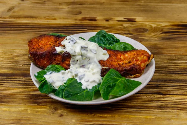 Ahşap masada ıspanaklı ve tartar soslu ızgara somon filetosu.