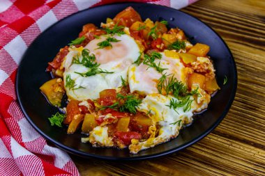 Ev yapımı shakshuka - kızarmış yumurta, soğan, dolmalık biber, domates ve dereotlu ahşap masa. Yahudi mutfağı
