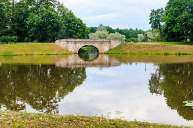 Rusya 'nın Gatchina kentindeki bir gölde taş kemer köprüsü.