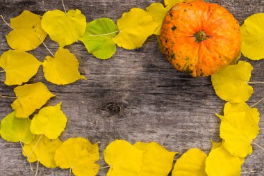 Kırsal ahşap arka planda sonbahar sarı yaprakları ve balkabağı çerçevesi. Üst görünüm, alanı kopyala