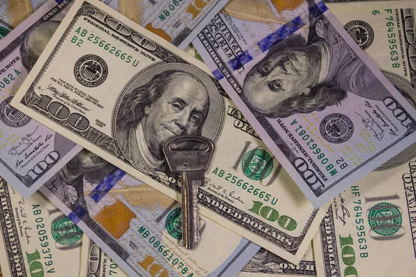 Yüz dolarlık banknotların arka planında anahtar var. Ev alma veya kiralama kavramı