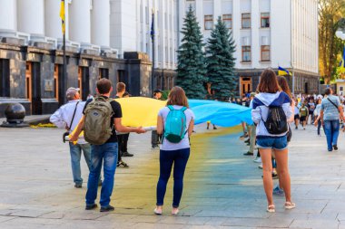 Kiev, Ukrayna - 23 Ağustos 2019: Ukrayna 'nın Kiev kentinde düzenlenen Ukrayna Bayrağı Günü sırasında başkanlık yönetimi yakınlarında büyük bir Ukrayna bayrağı taşıyan insanlar