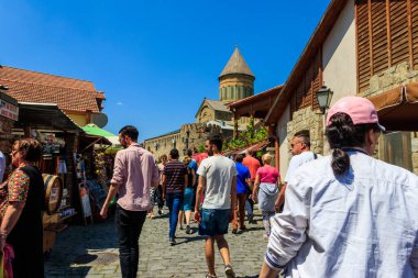 Mtskheta, Gürcistan - 1 Mayıs 2018: Gürcistan 'ın en eski şehirlerinden biri olan ve Dünya Mirası Alanı olarak belirlenen tarihi Mtskheta kentindeki hediyelik eşya dükkanlarıyla sokakta yürüyen turistler