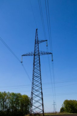 Mavi gökyüzüne karşı yüksek voltajlı güç hattı