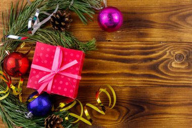 Noel kompozisyonu köknar ağacı dalları, hediye kutusu ve Noel süslemeleri ahşap masada. Üst görünüm, alanı kopyala