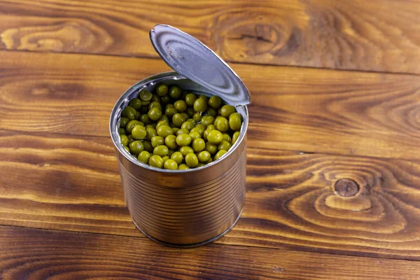 木製のテーブルの上に緑のエンドウ豆のオープン錫缶 — ストック写真