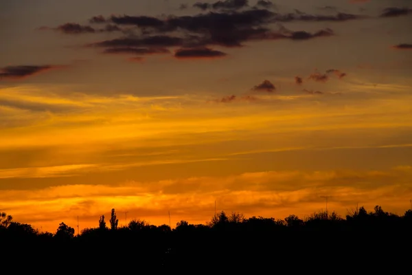 村や木々のシルエットにオレンジの夕日 — ストック写真