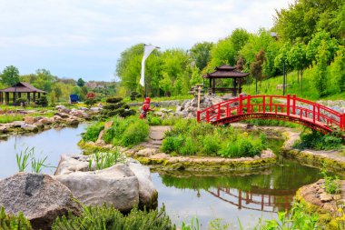 Japon bahçesindeki bir göletin yanında kırmızı köprü ve çardak.