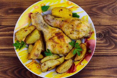 Ahşap masa üzerinde bir tabakta patates ile Fırında tavuk baget