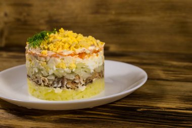 Ahşap masada geleneksel Rus salatası Mimoza. Sardalya, soğan, patates, havuç, peynir, yumurta ve mayonez ile katmanlı salata