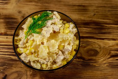 Tavuk göğsü, tatlı mısır, konserve ananas, peynir ve ahşap masada mayonez ile Şenlikli salata