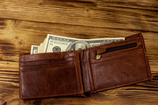 Opened wallet with american dollars on wooden table