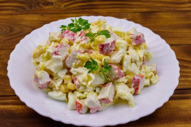 Yengeç saplı salata, tatlı mısır, Çin lahanası, yumurta ve mayonez ahşap masada.