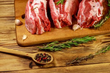 Baharatlı çiğ domuz kaburgası, sarımsak ve ahşap masada biberiye.